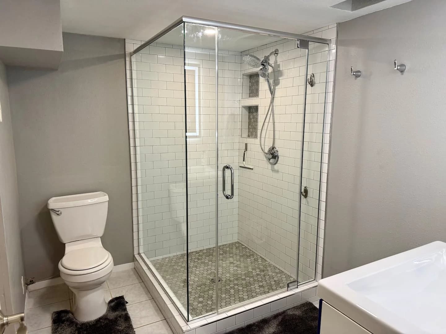 Downstairs bathroom with a glass-enclosed walk-in shower and white subway tile