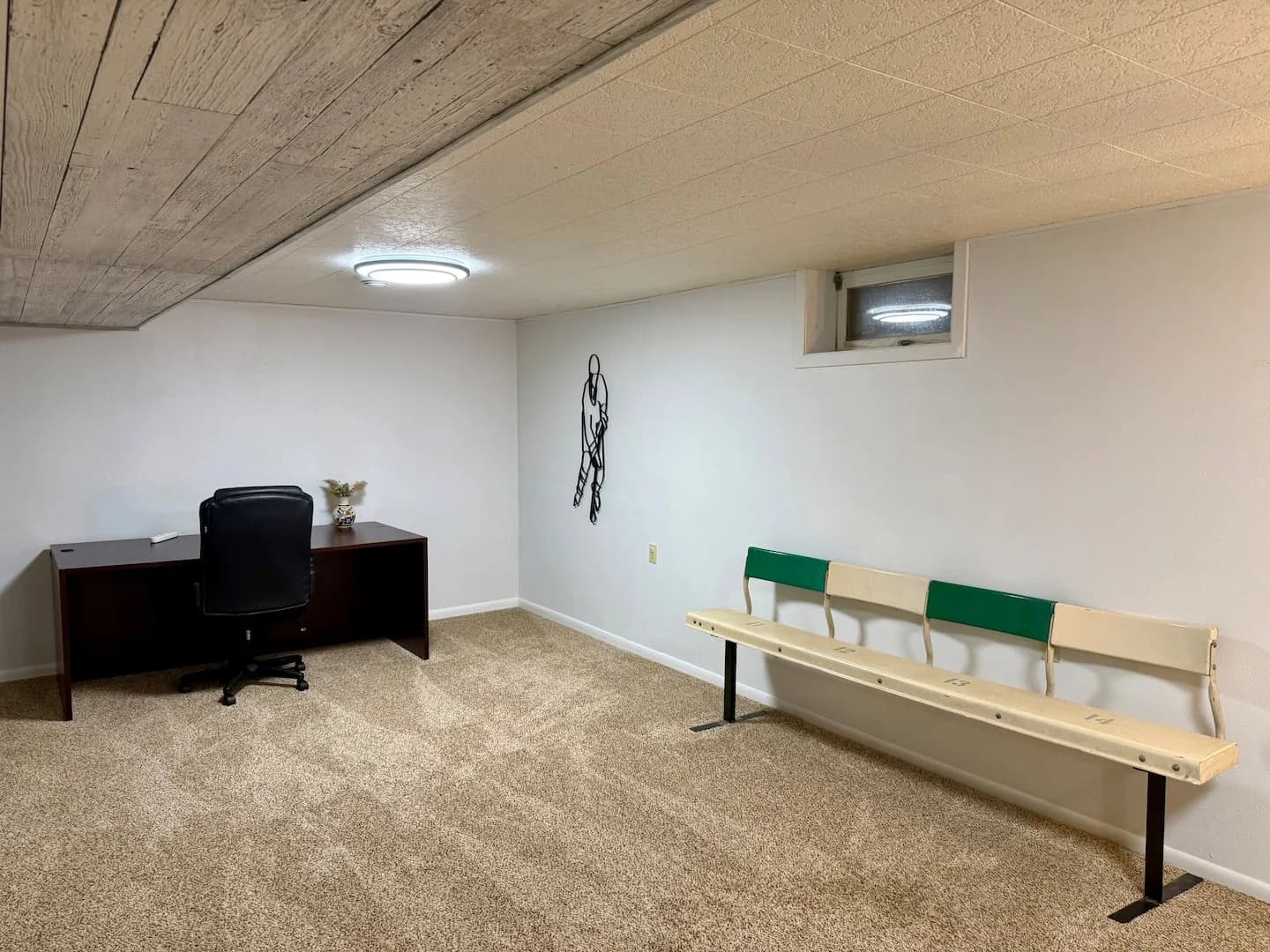 Original green-and-cream arena bench beside the desk in the basement