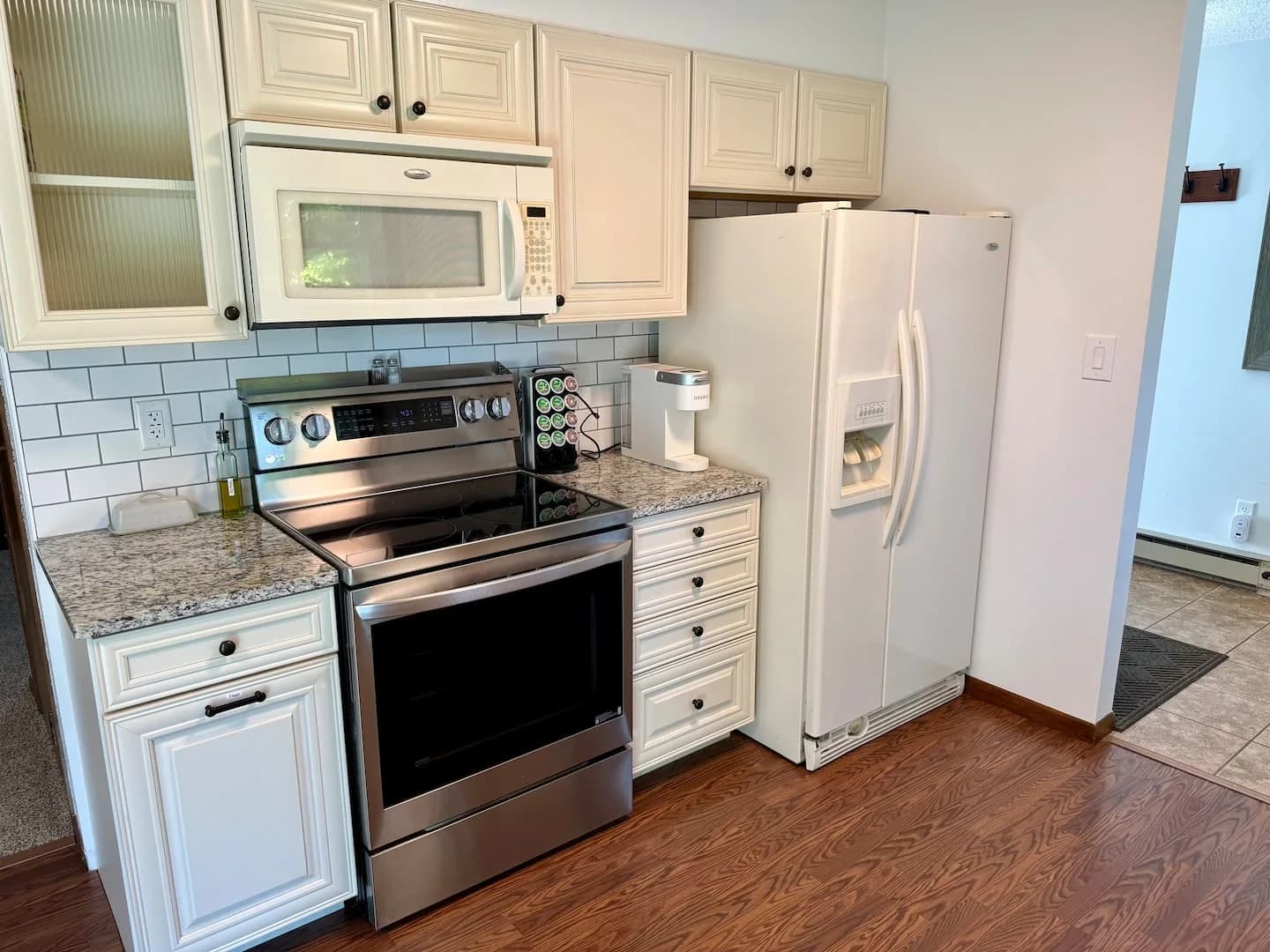 Remodeled kitchen with cream cabinets, a stainless steel range, microwave, and refrigerator
