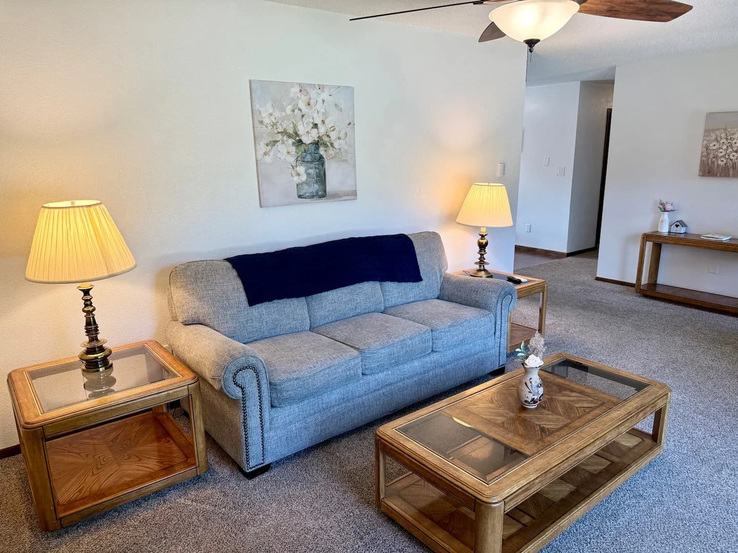 Upstairs living area with a blue sofa, wooden coffee table, and two table lamps