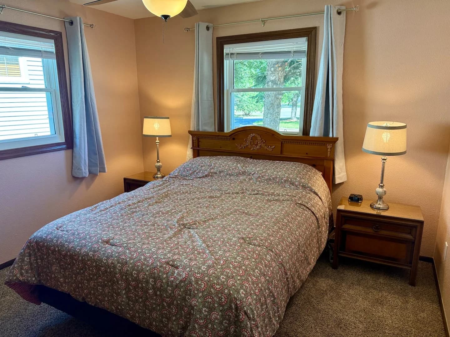 Queen bed with a wooden headboard and patterned quilt between two bedside tables